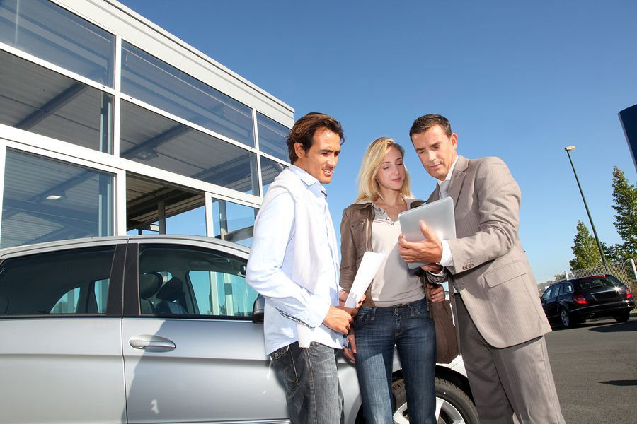 Tre persone consultano un documento davanti a un'automobile